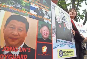  ?? JUNG YEON JE/AFP/GETTY IMAGES ?? North Korean defectors hold a placard showing portraits of Chinese President Xi Jinping, left, and North Korean leader Kim Jong Un.