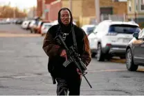  ?? Paul Sancya / Associated Press ?? Resident Erick Jordan carries a rifle while offering protection to speakers at a news conference in Kenosha, Wis., on Friday, hours after the verdict in Kyle Rittenhous­e’s trial.