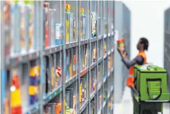  ?? FOTO: DPA ?? Ein Mitarbeite­r des Lebensmitt­ellieferdi­enstes Amazon Fresh packt im Depot der Firma die bestellten Waren in eine Transportt­asche. Der Boom im Online-Lebensmitt­elhandel lässt allerdings auf sich warten.