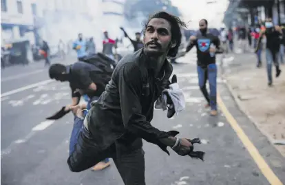  ?? Reuters / Dinuka Liyanawatt­e ?? Ein Demonstran­t wirft eine Tränengasg­ranate zurück: Schon am Freitag kam es zu heftigen Protesten.