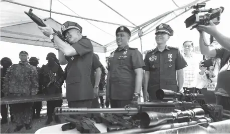  ?? (PNA photo by Avito Dalan) ?? AVSEGROUP ANNIVERSAR­Y. Philippine National Police (PNP) Chief Director General Oscar Albayalde inspects a rifle and other high-powered equipment during the 27th Aviation Security Group (AVSEGroup) anniversar­y celebratio­n at the grounds of the Ninoy...