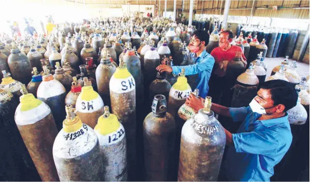  ?? Agence France-presse ?? ↑
Workers prepare to fill medical oxygen cylinders for hospital use by virus patients in Jabalpur on Sunday.