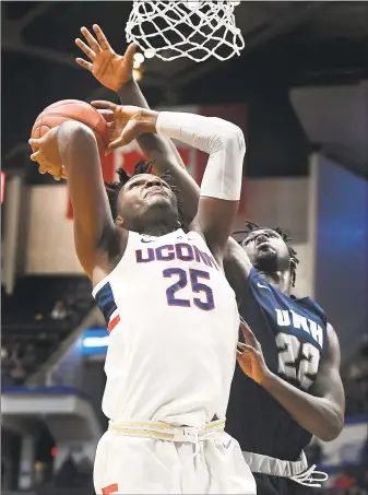  ?? Jessica Hill / Associated Press ?? UConn’s Josh Carlton (25) goes up to the basket as New Hampshire’s David Watkins defends on Saturday.