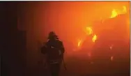  ?? (AFP) ?? A rescuer putting out a fire in a building as a result of falling debris after a drone attack targetting the Ukrainian capital in Kiev.