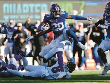  ?? ADAM HUNGER/AP ?? Giants safety Julian Love leaps over Ravens quarterbac­k Lamar Jackson as he returns an intercepti­on 27 yards to the 13-yard line, setting up the winning touchdown as New York rallied past Baltimore in East Rutherford, N.J.