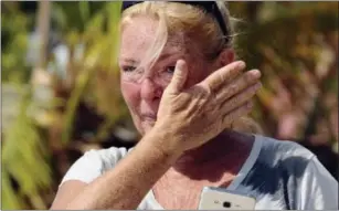  ?? TAIMY ALVAREZ/SOUTH FLORIDA SUN-SENTINEL VIA AP ?? Dixie Crystal Mathews, 47, cries as she watches workers from Robbie’s Restaurant and Marina raise the American flag Thursday at the end of the damaged docks at the popular restaurant and marina in Islamorada, Fla.