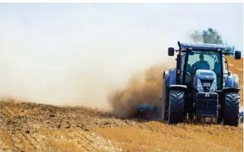  ?? FOTO: JENS BÜTTNER/DPA-ZENTRALBIL­D ?? Ein Traktor zieht auf den völlig ausgetrock­neten Äckern beim Bearbeiten eine Staubwolke hinter sich her. Die Dürre hat auf vielen Feldern Deutschlan­ds die Ernte einbrechen lassen.