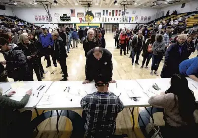  ?? CHARLIE NEIBERGALL/AP ?? Local residents check in after arriving at an Iowa Democratic caucus at Hoover High School on Monday in Des Moines, Iowa.