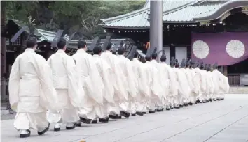  ?? — AFP ?? Yasukuni Shrine priests walk towards the main shrine to perform a Shinto ritual during the four-day autumn festival at the shrine in Tokyo, Japan, on Wednesday.