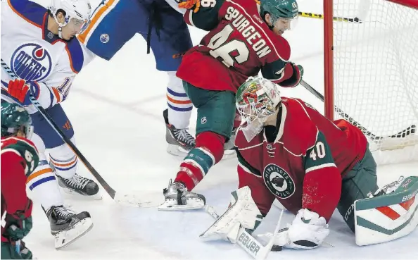  ?? JIM MONE/THE ASSOCIATED PRESS ?? Minnesota Wild goalie Devan Dubnyk, right, smothers the puck on a shot by Edmonton Oilers’ Nail Yakupov, left, in the third period of NHL hockey action on Tuesday in St. Paul, Minn. The Wild won 4-3.
