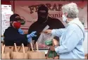  ??  ?? Ferrari Farms Tori Kuhn accepts payment as Leon Kuhn serves a customer at the “Essential” Farmers Market.