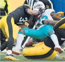  ??  ?? Miami Dolphins running back Jay Ajayi gets hit hard by Pittsburgh free safety Mike Mitchell, left. He had only 33 yards on 16 carries Sunday.