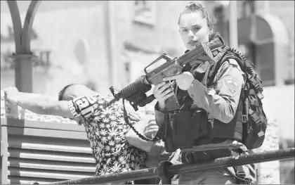  ??  ?? Una agente fronteriza israelí apunta con su arma a un palestino mientras sus colegas revisan las identifica­ciones del hombre, quien se dirigía hacia la mezquita Al Aqsa ■ Foto Afp