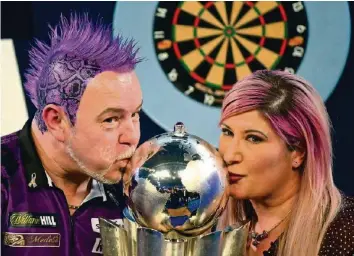  ?? GETTY ?? Darts-Weltmeiste­r Peter «Snakebite» Wright küsst den Siegerpoka­l mit seiner Frau Joanne.