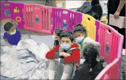  ??  ?? PENNED IN: Unaccompan­ied migrants ranging in age from 3 to 9 are kept in a playpen while older kids crowd together on benches waiting to be processed at a federal detention center Tuesday in Donna, Texas.