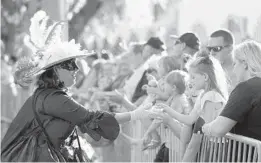  ?? GERALD HERBERT/AP ?? A woman dressed in period costume hands a trinket to a child during a parade dubbed “Tardy Gras,” to compensate for a canceled Mardi Gras due to the COVID-19 pandemic, on Friday in Mobile, Alabama.