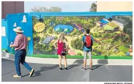  ?? DEWAYNE BEVIL/STAFF ?? Visitors to Disney’s Hollywood Studios look at a map of Toy Story Land on the wall that separates them from the constructi­on of the attraction.