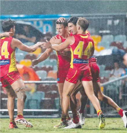  ?? Pictures: BRENDAN RADKE; GETTY ?? Suns’ Nick Holman (top centre) celebrates after kicking a goal. And (below) laying a tackle in Cairns.