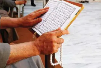  ?? —AP ?? GAZA: A Palestinia­n man reads verses of the Quran during the month of Ramadan at Al Emari mosque in Gaza. Muslims across the world are observing the holy fasting month of Ramadan, where they refrain from eating, drinking and smoking from dawn to dusk.