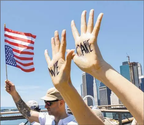  ?? HOWARD SIMMONS/DAILY NEWS ?? Upside down flag (a sign of distress) is carried by protester (above), while others crossed Brooklyn Bridge. Lin-Manuel Miranda (below right) spoke out in Washington, D.C.