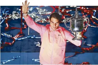  ?? AFP ?? Rafael Nadal (left photo) celebrates his victory over Kevin Anderson and (above) holds the championsh­ip trophy after claiming his third US Open championsh­ip.