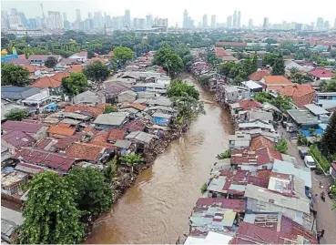  ?? /Bloomberg ?? Extreme weather: Residentia­l buildings along the swollen Ciliwung River in Jakarta, Indonesia. Climate change research shows that heavy precipitat­ion and tropical cyclones, on top of rising sea levels, are already having devastatin­g consequenc­es.