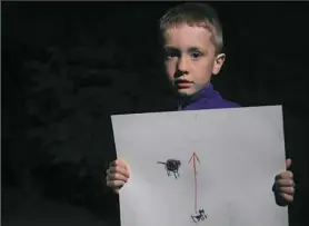  ?? Stephanie Strasburg/Post-Gazette ?? Jayden Knapp, 6, holds a drawing he made of his late cat, Ollie, with an arrow pointing from the cat toward heaven on Monday in his family’s backyard in Brookline.