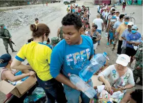 ??  ?? Voluntario­s reparten agua y comida a los damnificad­os que perdieron sus hogares en Canoa, Ecuador, por el sismo del pasado sábado.