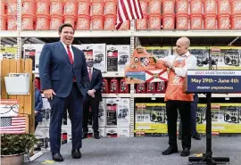  ?? GREG LOVETT The Palm Beach Post ?? Florida Gov. Ron DeSantis received a personaliz­ed Home Depot apron from Jacob Roberts, a regional manager for the company, during his stop at the Boca Raton store Friday.