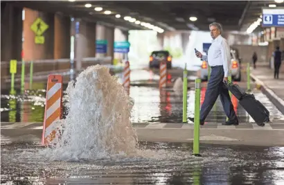  ?? CHERYL EVANS/THE REPUBLIC ?? Water spews at a manhole at Phoenix Sky Harbor’s Terminal 4 Thursday when a monsoon storm flooded roadways around the airport.