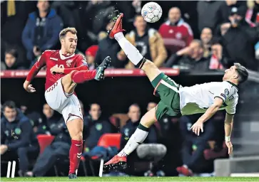  ??  ?? High point: Denmark’s Christian Eriksen and Stephen Ward engage in an acrobatic tussle at Copenhagen’s Parken Stadium last night