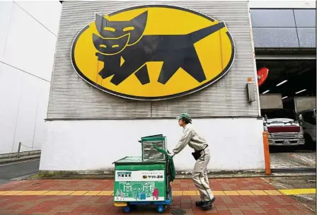  ??  ?? Rate review: A Yamato deliverer is seen under the company’s logo at a business district in Tokyo. The parcel giant has spent most of the year negotiatin­g new rates with Amazon’s Japan unit and other large customers. — Reuters