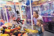  ??  ?? Eli Schroeder, 5, of Baltimore gets excited as he almost wins a prize in a claw machine while playing with his mom, Sara Schroeder, at Funland.