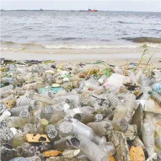  ?? ISSOUF SANOGO/AFP/GETTY IMAGES ?? Plastic bottles and other waste lies on the sand after being washed ashore near the port of Abidjan, Ivory Coast. Scenes like this are helping make consumer plastics into a pariah.