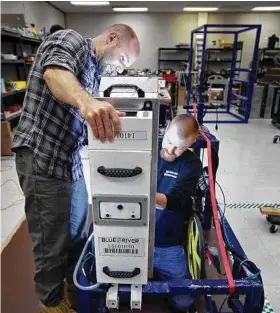  ??  ?? LiPo Ching / Bay Area News Group Blue River Technology software engineer Willy Pell, left, and mechanical engineer Bryon Majusiak, right, repair a seed line module from a lettuce thinning robot.