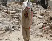  ?? (Aboud Hamam/Reuters) ?? A MAN CARRIES his belongings through rubble in Raqqa, Syria, earlier this week.