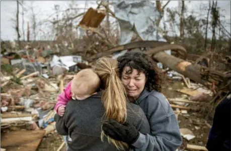  ?? DAVID GOLDMAN — THE ASSOCIATED PRESS ?? Carol Dean, right, cries while embraced by Megan Anderson and her 18-month-old daughter Madilyn, as Dean sifts through the debris of the home she shared with her husband, David Wayne Dean, who died when a tornado destroyed the house in Beauregard, Ala., Monday.