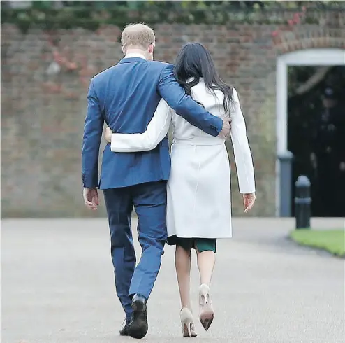  ?? ALASTAIR GRANT / THE ASSOCIATED PRESS ?? Britain’s Prince Harry, who is fifth in line for the British throne, strolls with Meghan Markle on the grounds of Kensington Palace Monday, after the announceme­nt that they will marry in the spring.