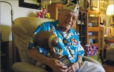  ?? ERIC RISBERG — THE ASSOCIATED PRESS ?? Mickey Ganitch, 101, holds a football trophy he received at his home in San Leandro last month. Ganitch had been preparing to play a game on Dec. 7, 1941. Instead, he spent the morning in his football uniform spotting planes for anti-aircraft gunners.