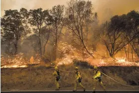  ?? NOAH BERGER/THE ASSOCIATED PRESS ?? Firefighte­rs battle a wildfire over the weekend as it threatens to jump a street near Oroville, Calif. More than 5,000 people evacuated as flames raced through grassy foothills in the Sierra Nevada.