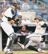  ?? Jim McIsaac / Getty Images ?? Joey Rickard of the Orioles slides home with a run past Gary Sanchez of the Yankees in the eighth inning of Sunday’s game at Yankee Stadium in New York.