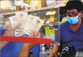  ?? Mark J. Terrill Associated Press ?? MAHER DIAB holds up his lottery tickets at Bluebird Liquor in Hawthorne on Friday. There have been 37 straight Powerball drawings without a jackpot winner.