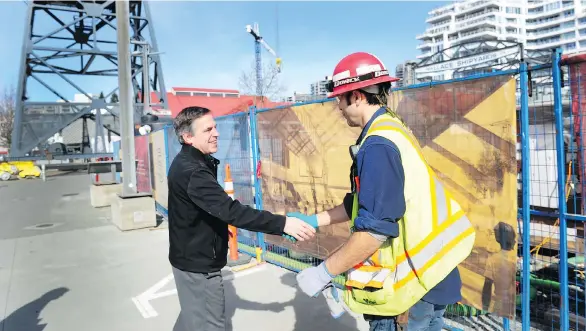  ?? NICK PROCAYLO ?? “We have to find new ways of allowing people to live here, to be housed here,” says North Vancouver Mayor Darrell Mussatto, seen greeting a constructi­on worker.