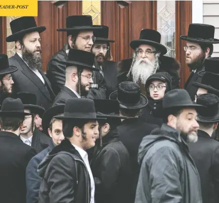  ?? JEENAH MOON / REUTERS ?? Rabbi Chaim Rottenberg and others gather outside his home in Monsey, N.Y., where an attacker burst in Saturday evening and stabbed five people.