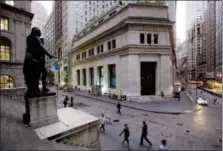  ?? MARK LENNIHAN — THE ASSOCIATED PRESS FILE ?? People walk to work on Wall Street beneath a statue of George Washington, in New York.