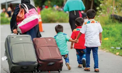  ?? Photograph: Geoff Robins/AFP/Getty Images ?? Asylum seekers walk along Roxham Road near Champlain, New York, in 2017, making their way towards the Canadian border.