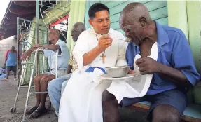  ??  ?? A brother of the Missionari­es of the Poor feeds an elderly man.