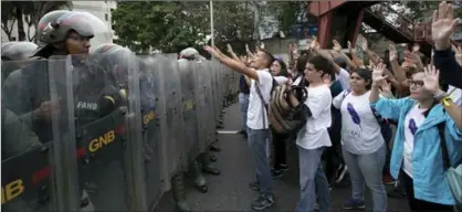  ?? ARIANA CUBILLOS, THE ASSOCIATED PRESS ?? University students shout, "No dictatorsh­ip," at a line of Venezuelan national guard officers in riot gear during a protest Friday outside the Supreme Tribunal of Justice in Caracas. Venezuelan­s have been thrust into a new round of political turbulence.