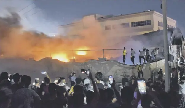  ??  ?? 0 People gather as a fire engulfs the coronaviru­s isolation ward of Al-hussein hospital in the city of Nasiriyah