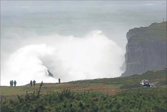  ?? KIKO DELGADO / EFE ?? La silueta de las personas que observan el mar durante el temporal contrasta con el enorme tamaño de las olas